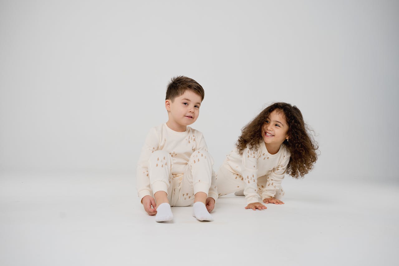 Smiling children wearing matching pajamas in a bright studio setting.