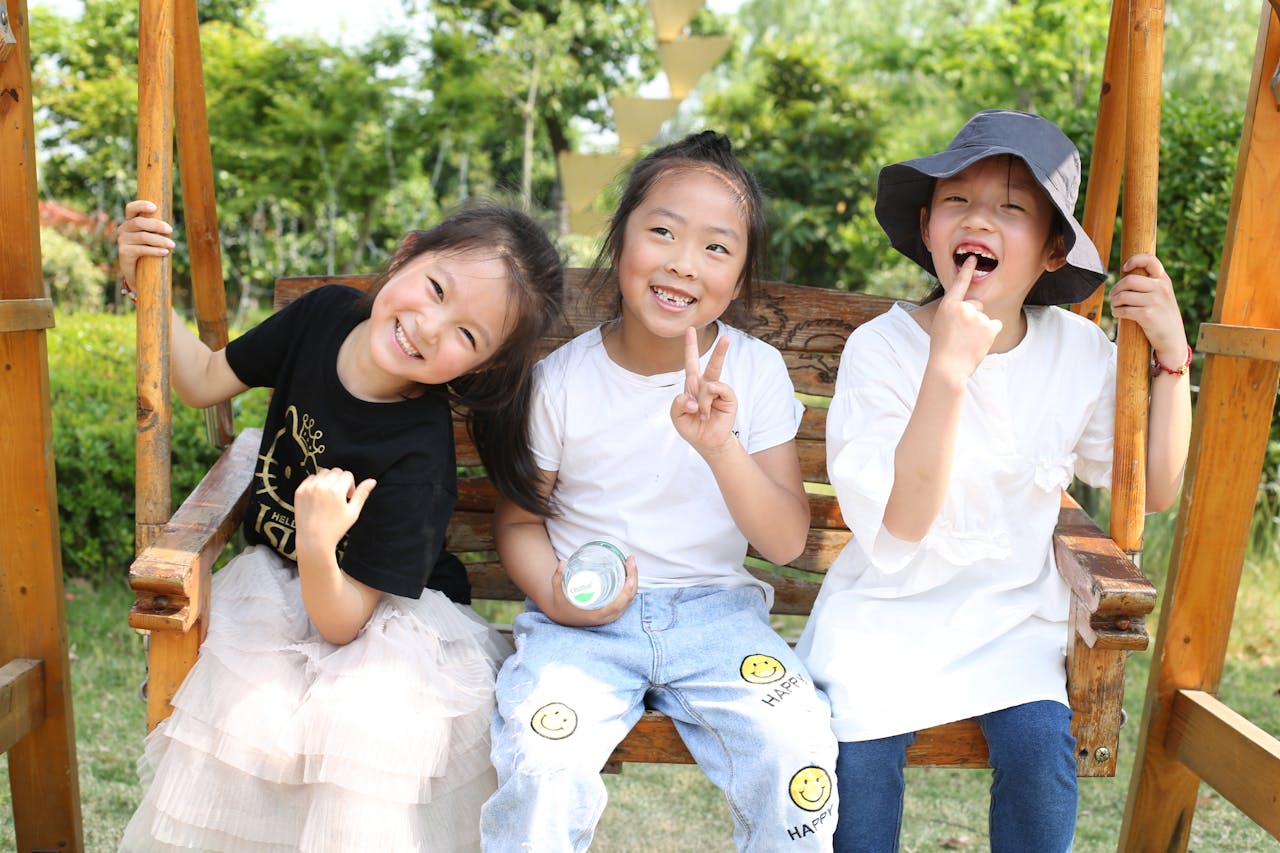 Three children enjoying a swing in the park, smiling and having fun under the sun.