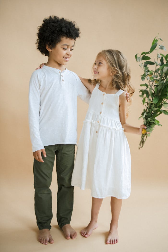 Adorable siblings in a studio, smiling and embracing. Warm, joyful portrait.