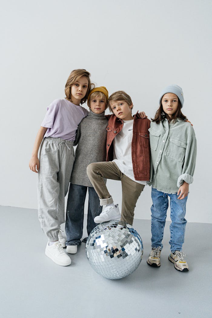 Fashionably dressed children pose with a disco ball, showcasing modern style.