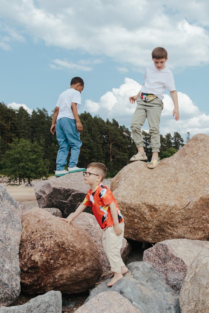 Three boys having fun climbing rocks outdoors in a natural setting.